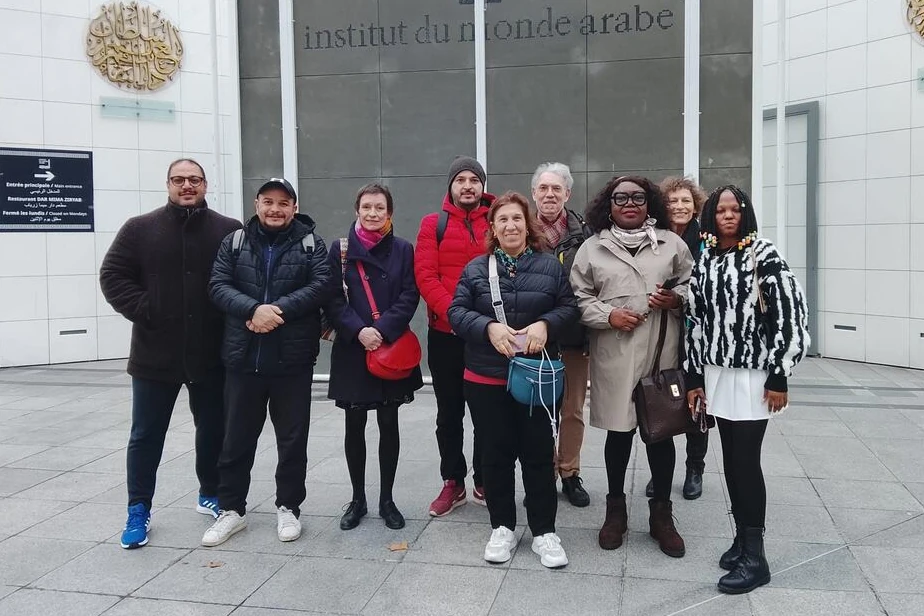 Bénévoles et accueillis devant la façade de l'Institut du Monde Arabe.