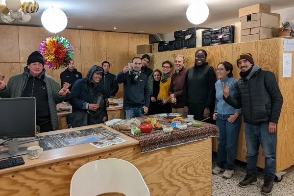 Fête de Noël à la Bagagerie le 24 décembre 2025, bénévoles et accueillis autour d'un buffet.